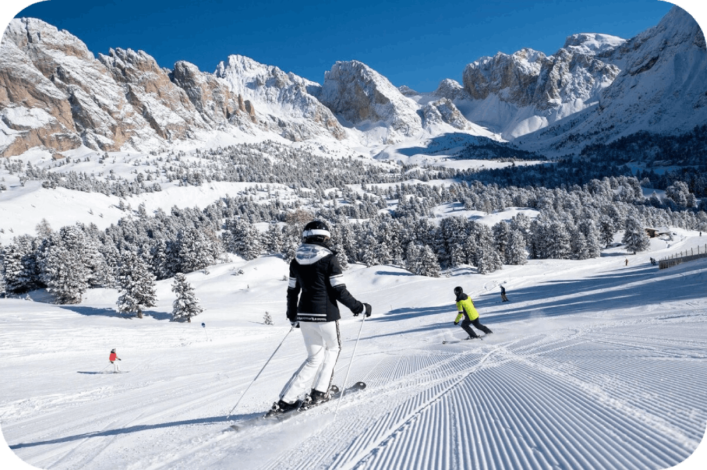 People Skiing on a mountain slop with a beautiful view of snow covered mountains